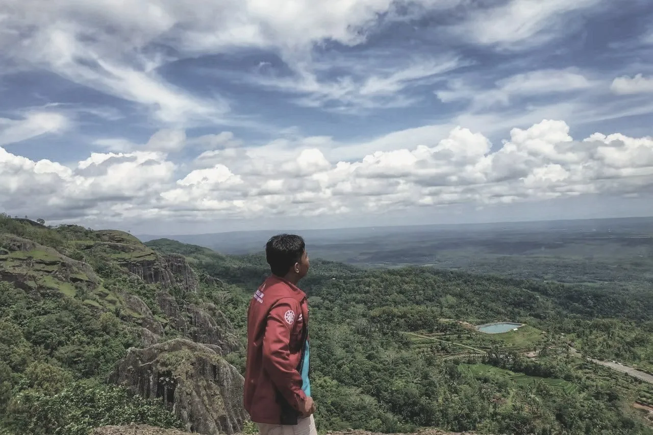 Engki Nandatama on a clifftop at Nglanggeran, looking out over a forested valley
